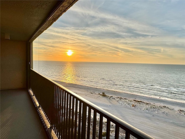 balcony at dusk featuring a water view