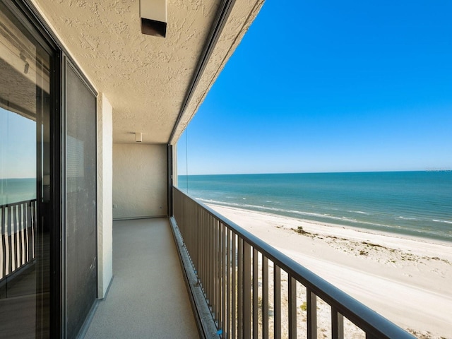 balcony featuring a view of the beach and a water view