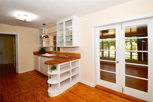 interior space with white cabinetry, sink, dark hardwood / wood-style flooring, butcher block countertops, and pendant lighting