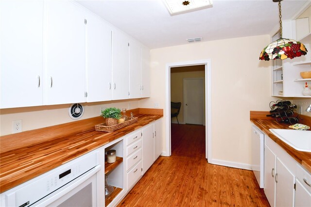 kitchen with wood counters, light wood-type flooring, pendant lighting, dishwasher, and white cabinets