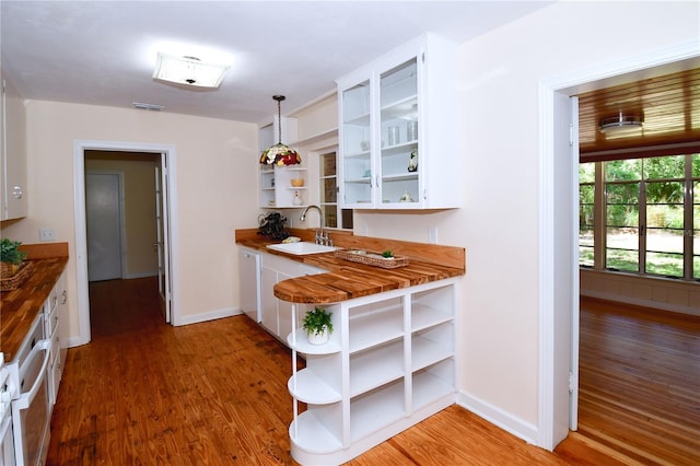 kitchen with white cabinets, decorative light fixtures, dark hardwood / wood-style floors, and sink