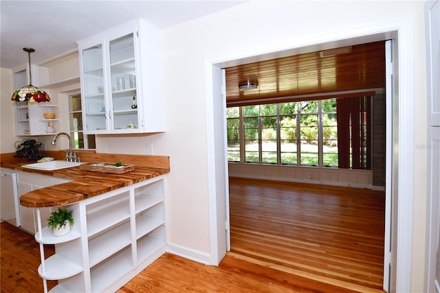 bar featuring dishwasher, white cabinets, sink, hanging light fixtures, and light hardwood / wood-style floors