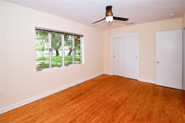 unfurnished bedroom featuring ceiling fan, a closet, and hardwood / wood-style flooring