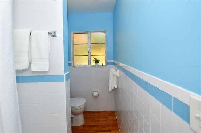 bathroom featuring hardwood / wood-style floors, toilet, and tile walls