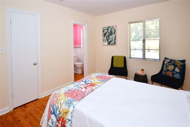 bedroom with light wood-type flooring and ensuite bathroom