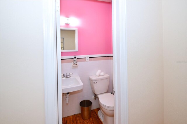 bathroom with hardwood / wood-style floors, toilet, sink, and tile walls