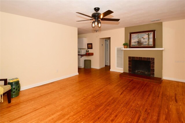 unfurnished living room with hardwood / wood-style flooring, ceiling fan, and a fireplace