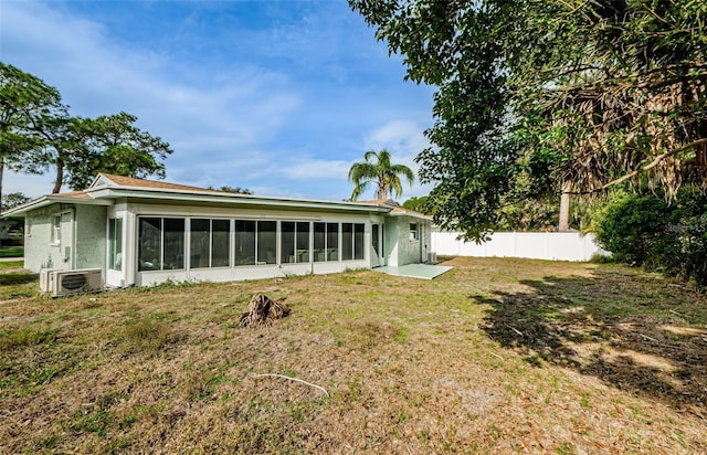 back of property with a sunroom, a yard, and ac unit