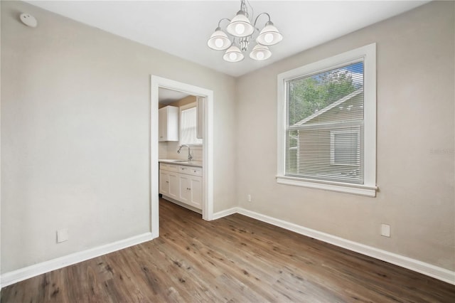 unfurnished dining area featuring sink, light hardwood / wood-style floors, and a notable chandelier