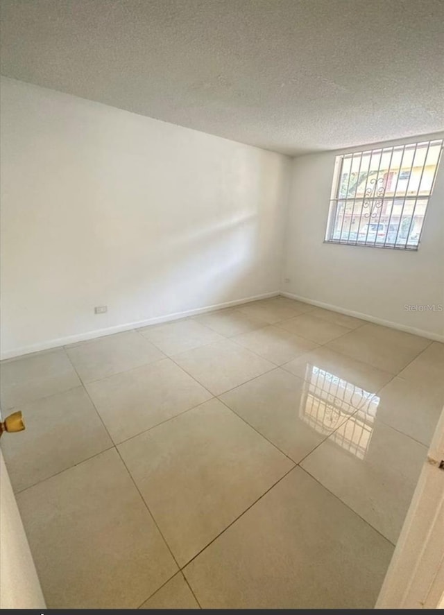 empty room featuring light tile patterned floors and a textured ceiling