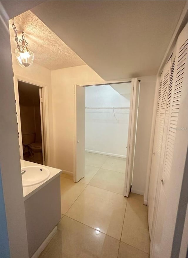 bathroom with tile patterned floors, vanity, a textured ceiling, and toilet