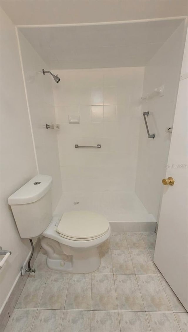 bathroom featuring tile patterned flooring, tiled shower, and toilet