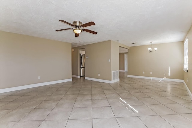 tiled empty room with ceiling fan with notable chandelier and a textured ceiling