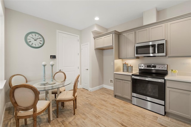 kitchen with light wood-type flooring, stainless steel appliances, and gray cabinetry