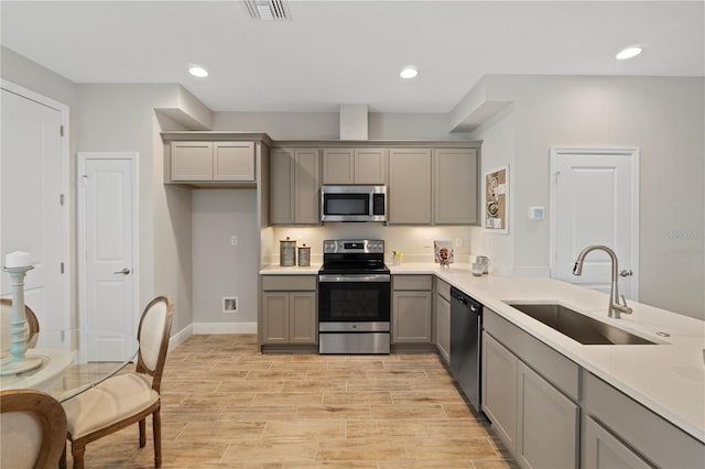 kitchen with gray cabinets, light hardwood / wood-style floors, sink, and appliances with stainless steel finishes