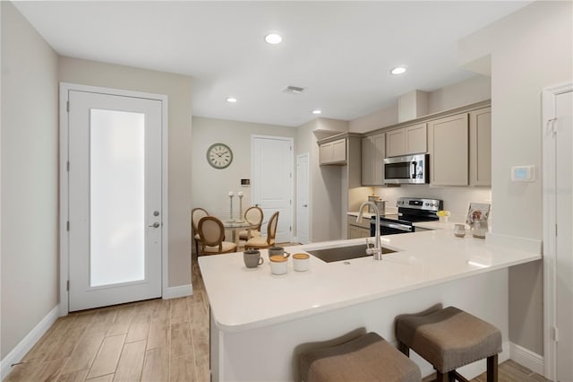 kitchen featuring kitchen peninsula, gray cabinetry, stainless steel appliances, sink, and light hardwood / wood-style flooring