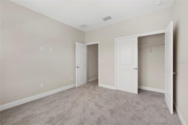 unfurnished bedroom with light colored carpet and a closet