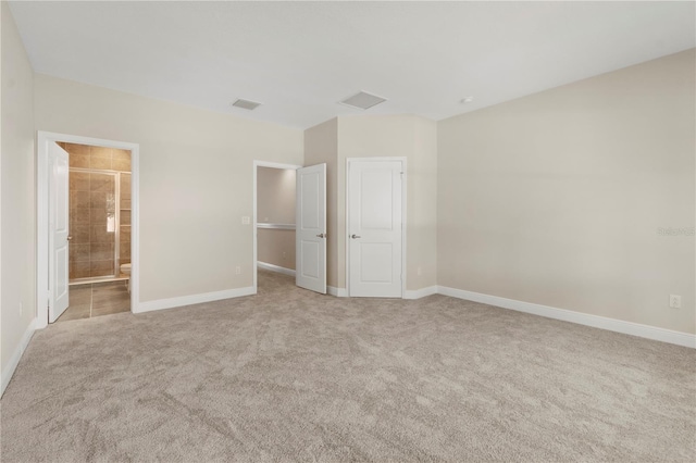 unfurnished bedroom featuring ensuite bath and light carpet