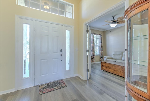 entrance foyer with ceiling fan, ornamental molding, and light hardwood / wood-style flooring