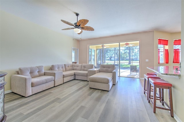 living room featuring ceiling fan, light wood-type flooring, and a wealth of natural light