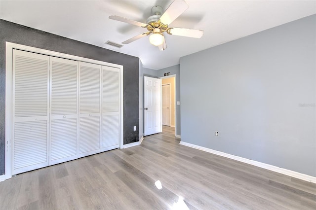 unfurnished bedroom featuring light wood-type flooring, a closet, and ceiling fan