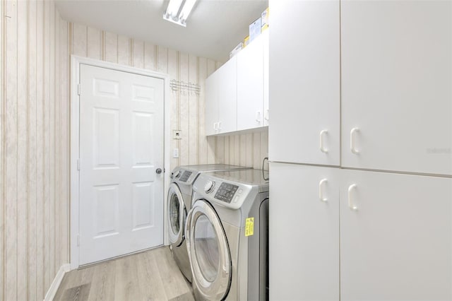 laundry room featuring cabinets, light hardwood / wood-style flooring, and washing machine and clothes dryer