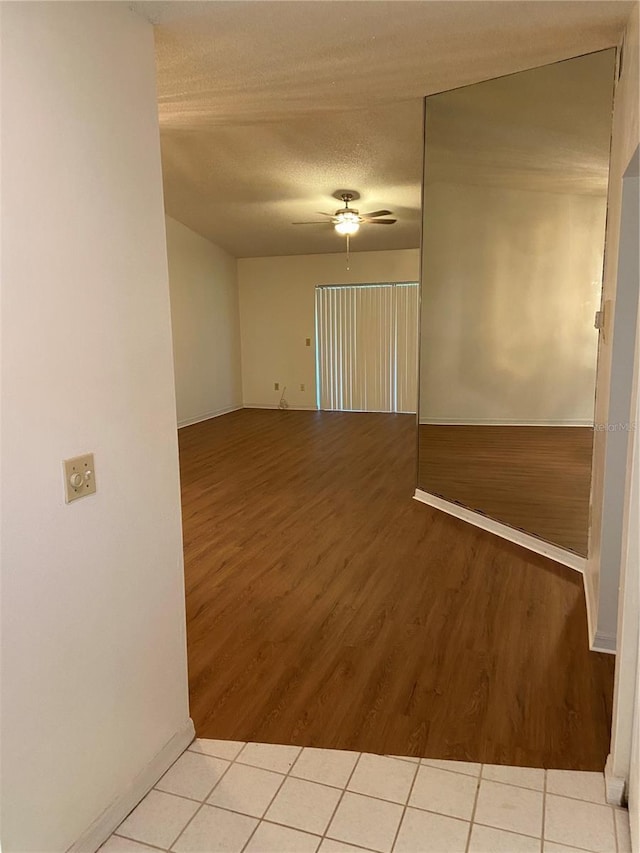 spare room featuring ceiling fan, light wood-type flooring, and a textured ceiling