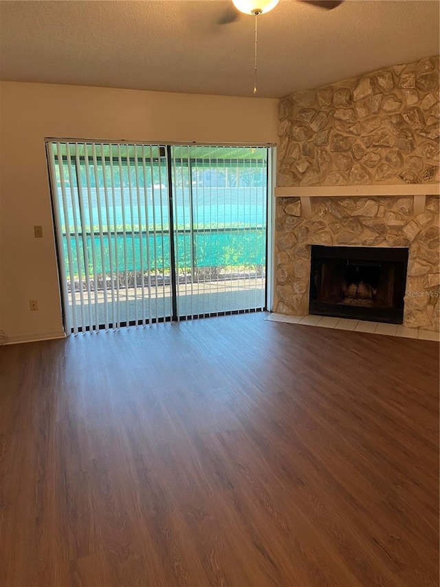 unfurnished living room featuring a stone fireplace, ceiling fan, a textured ceiling, and hardwood / wood-style flooring