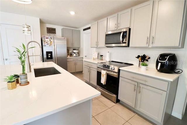 kitchen with appliances with stainless steel finishes, gray cabinetry, sink, decorative light fixtures, and light tile patterned flooring