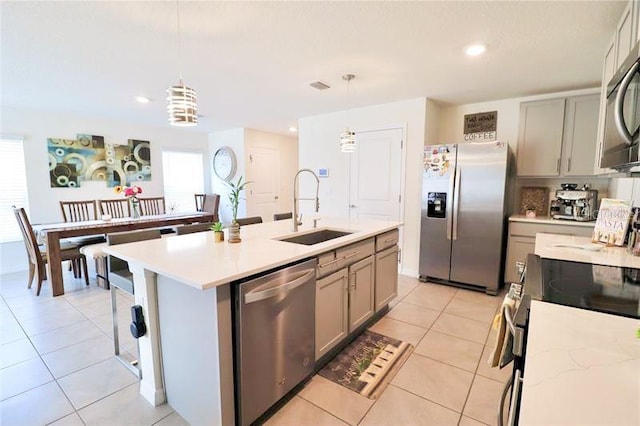 kitchen featuring stainless steel appliances, hanging light fixtures, gray cabinetry, and sink