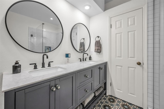 bathroom featuring tiled shower, vanity, and tile patterned flooring