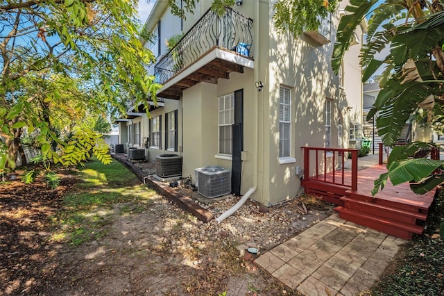 view of side of home featuring a balcony, central AC unit, and a wooden deck