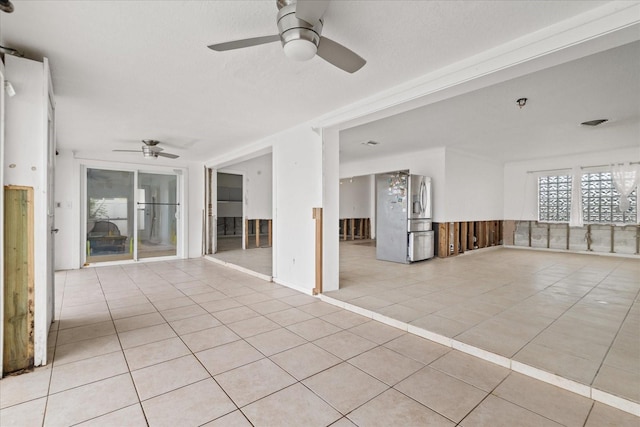 tiled empty room with ceiling fan and a textured ceiling