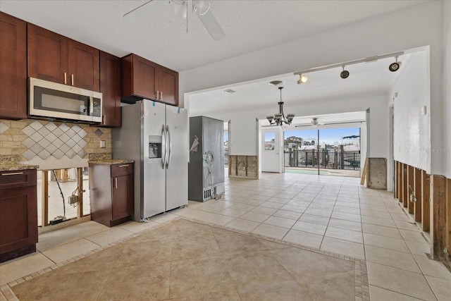 kitchen featuring appliances with stainless steel finishes, backsplash, rail lighting, ceiling fan with notable chandelier, and light tile patterned floors