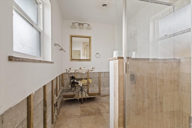 bathroom with tile walls, a shower with door, and plenty of natural light