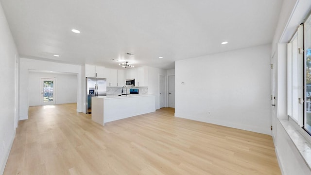 kitchen with sink, light wood-type flooring, white cabinetry, kitchen peninsula, and stainless steel appliances