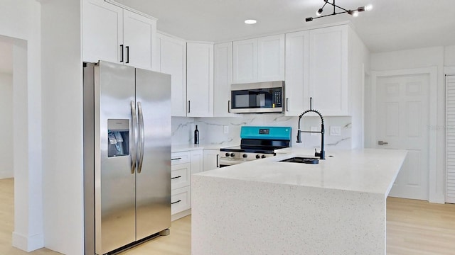 kitchen with appliances with stainless steel finishes, white cabinetry, light hardwood / wood-style flooring, and sink