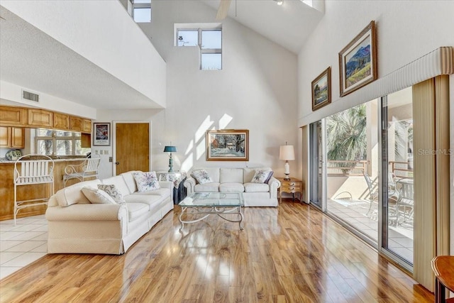 living room with beamed ceiling, light wood-type flooring, high vaulted ceiling, and plenty of natural light