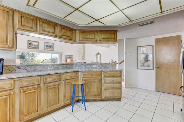 kitchen with light stone countertops, light tile patterned floors, and a textured ceiling