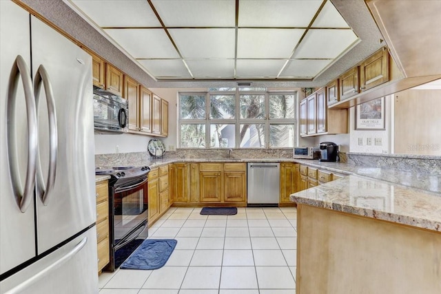 kitchen with black appliances, sink, light stone countertops, light tile patterned flooring, and kitchen peninsula