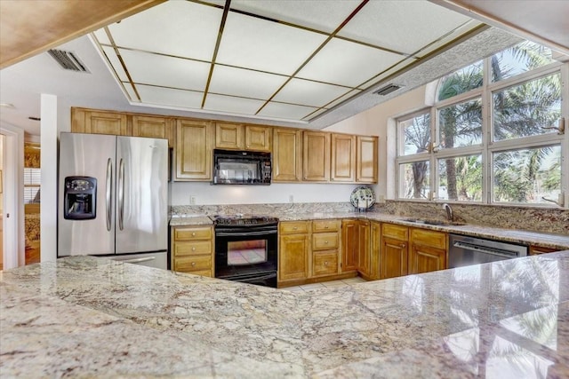 kitchen with sink, light stone counters, and black appliances