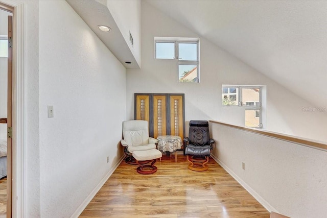 living area featuring lofted ceiling and light hardwood / wood-style flooring