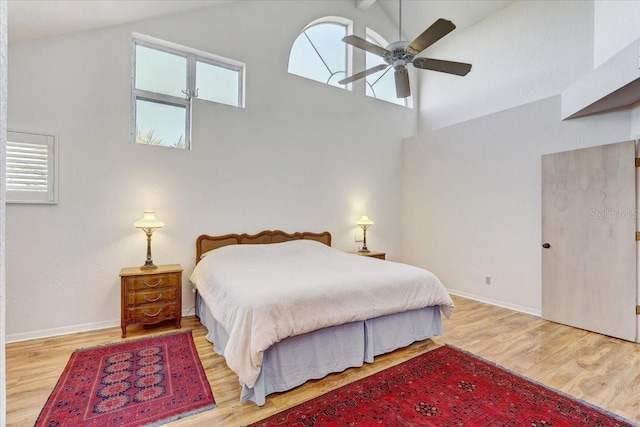 bedroom with ceiling fan, light hardwood / wood-style flooring, and high vaulted ceiling