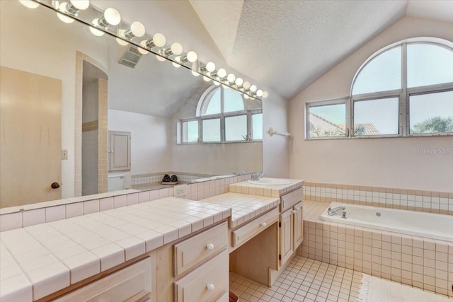 bathroom with vanity, lofted ceiling, a textured ceiling, and a wealth of natural light