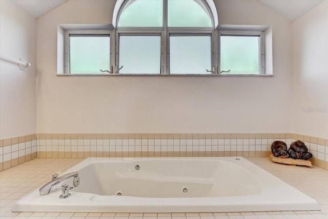 bathroom featuring tiled tub and vaulted ceiling