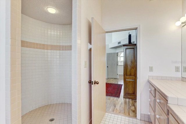 bathroom with tiled shower, wood-type flooring, a textured ceiling, and vanity