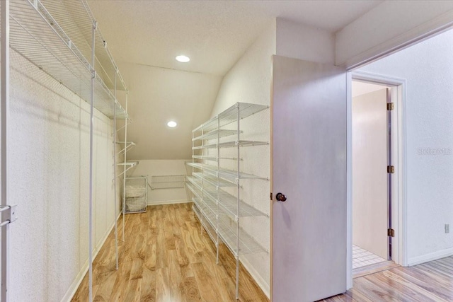 spacious closet with wood-type flooring and vaulted ceiling