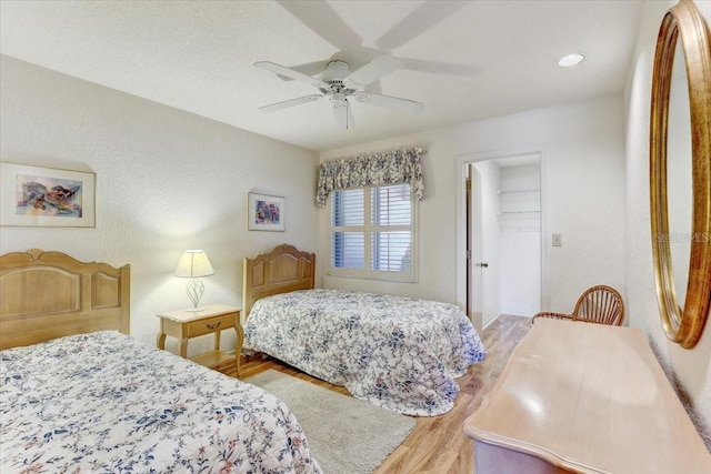 bedroom with a spacious closet, ceiling fan, wood-type flooring, and a closet