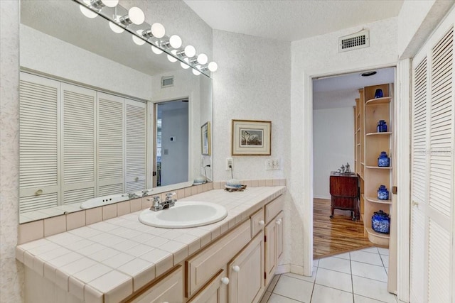 bathroom with tile patterned flooring, a textured ceiling, and vanity