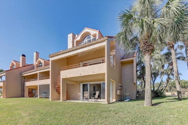 back of house with a lawn, a balcony, and a patio